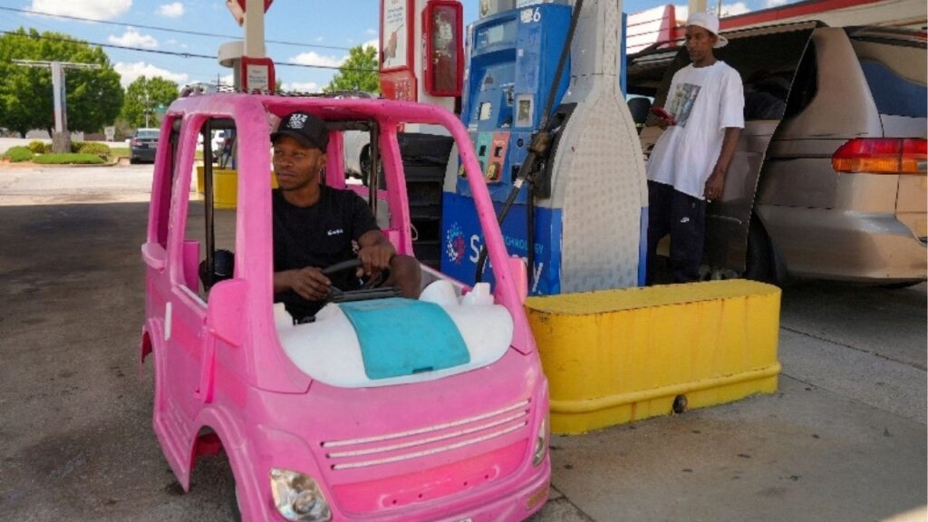 Mali Hightower, 30, poses with what he describes as a self-created gas saver, a pink Power Wheels Barbie Dream Camper, at a gas station in Ellenwood, Georgia, U.S., May 18, 2026. (Reuters/Jayla Whitfield-Anderson)