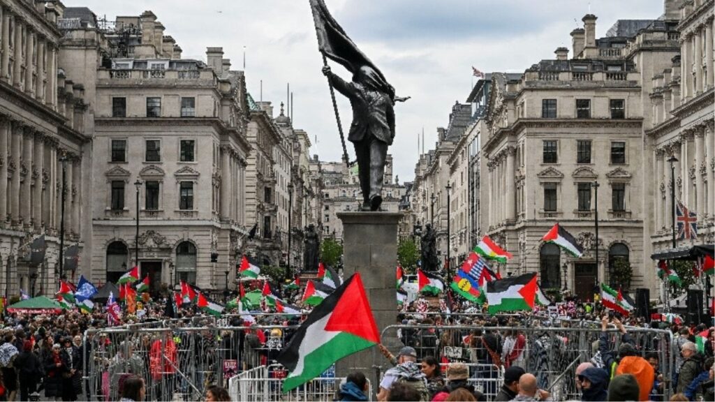 People hold Palestinian flags next to a statue, depicting a figure carrying a flag covering their face and stepping off a plinth, by British street artist Banksy during a march, held by Palestine Solidarity Campaign, to mark the 78th anniversary of the Nakba and against the "Unite the Kingdom" rally taking place in London organised by British anti-immigration activist Stephen Yaxley-Lennon, also known as Tommy Robinson, in London, Britain, May 16, 2026. REUTERS/Chris J Ratcliffe