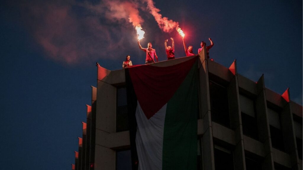 Protesters who hung a huge Palestinian flag at a building facing the Israeli embassy, lit flares during a protest over the interception of the Gaza aid flotilla, in Athens, Greece, May 21, 2026. (Reuters/Louisa Gouliamaki)
