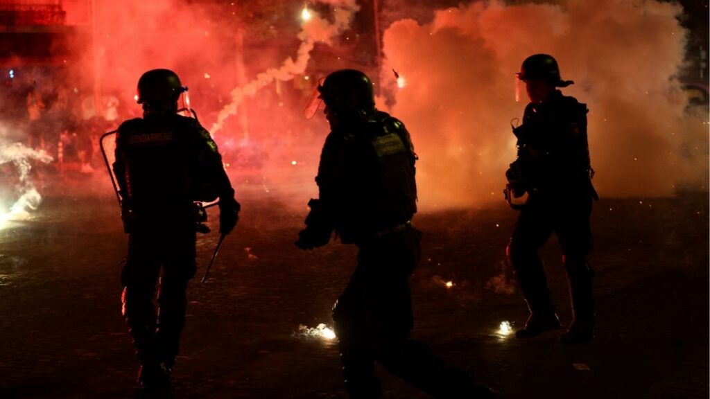 Soccer Football - UEFA Champions League - Paris St Germain fans celebrate winning the UEFA Champions League - Paris, France - May 31, 2026 Police officers protect themselves from flares after Paris St Germain won the UEFA Champions League REUTERS/Abdul Saboor