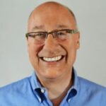 Portrait of Ted Lempert, president of Children Now. He's wearing glasses and an open blue collar dress shirt