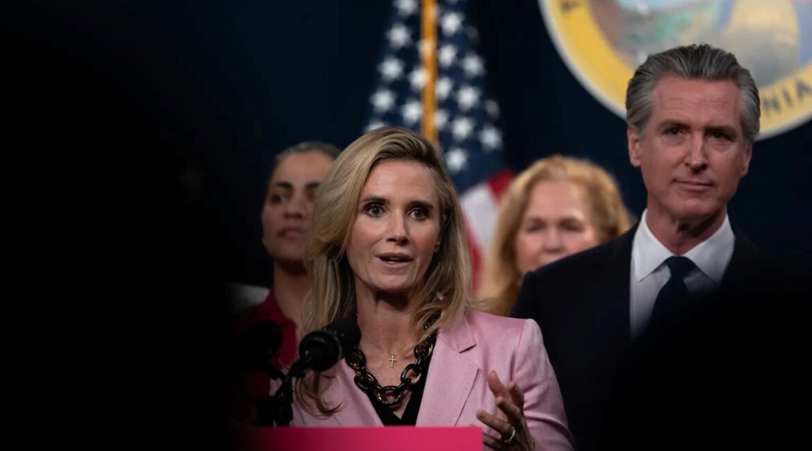 Image of a well-dressed woman and man standing at a podium with the American Flag and Seal of California in the background