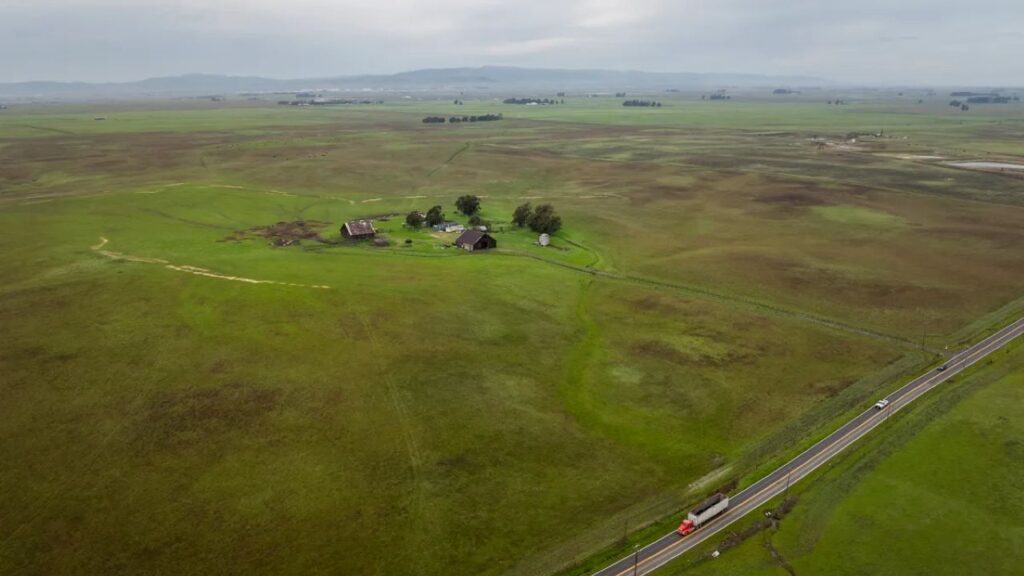 Aerial view of green farmland surrounded by farm buildings