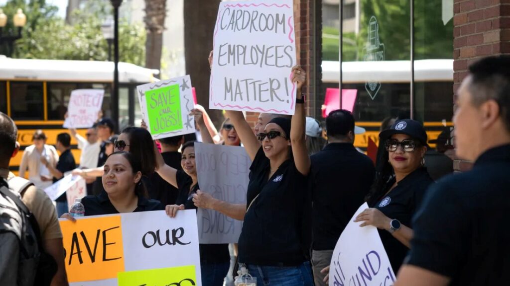 Image of cardroom employers rallying to save their jobs. They're carrying signs and standing in front of a Sacramento hotel.