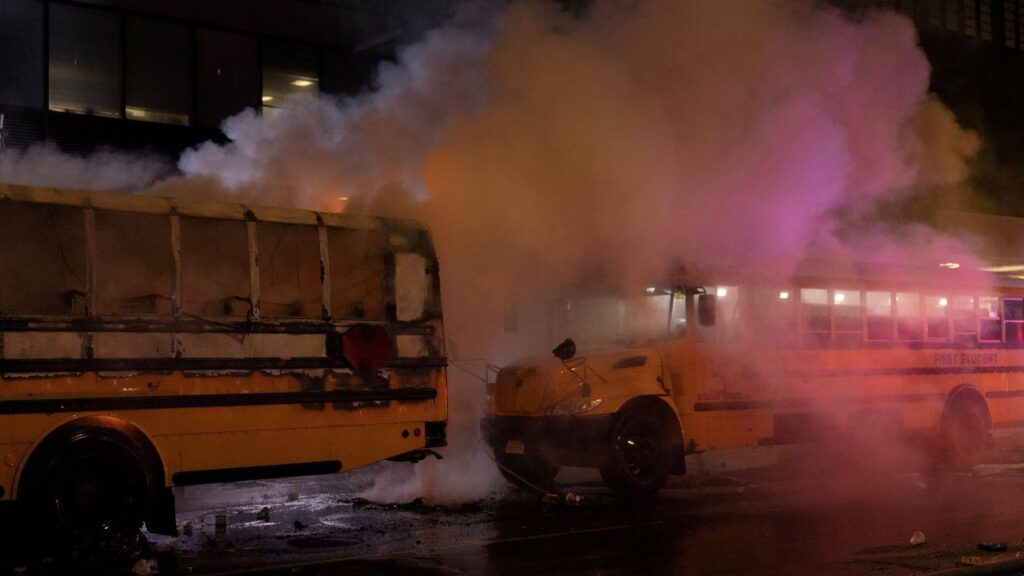 Image of a yellow school bus billowing smoke as a fire is being extinguished