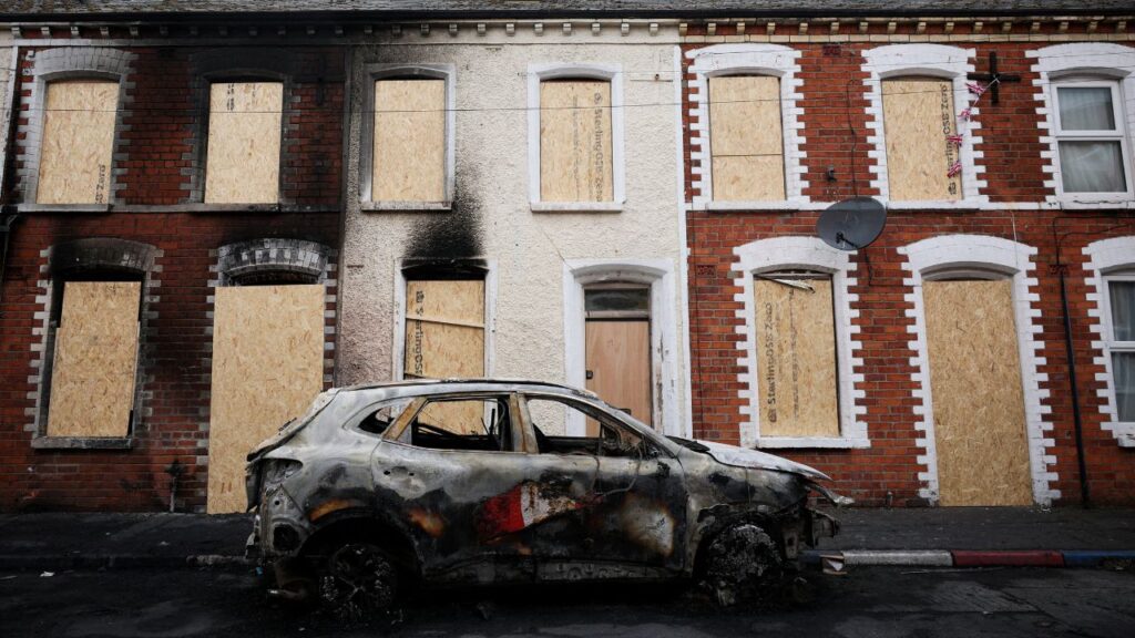 A burnt car stands in front of a boarded up house, in the aftermath of anti-immigrant protests following a knife attack on June 8, which left a man seriously injured and prompted police to declare a critical incident, at Lendrick street, east Belfast, Northern Ireland, June 10, 2026. REUTERS/Isabel Infantes