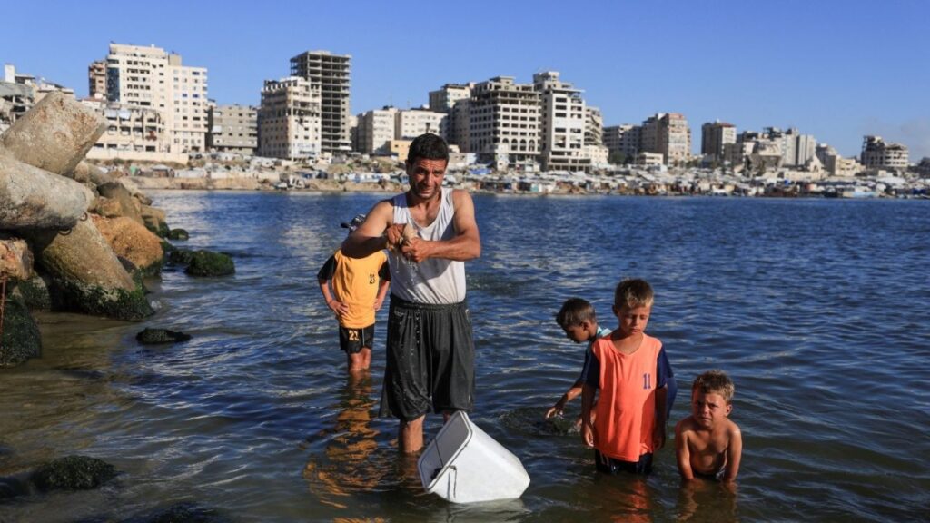 A displaced Palestinian, Shihab al-Suwaireki, washes clothes with his children at the seashore amid severe water shortages and summer heat in Gaza City, June 19, 2026. (Reuters/Dawoud Abu Alkas)