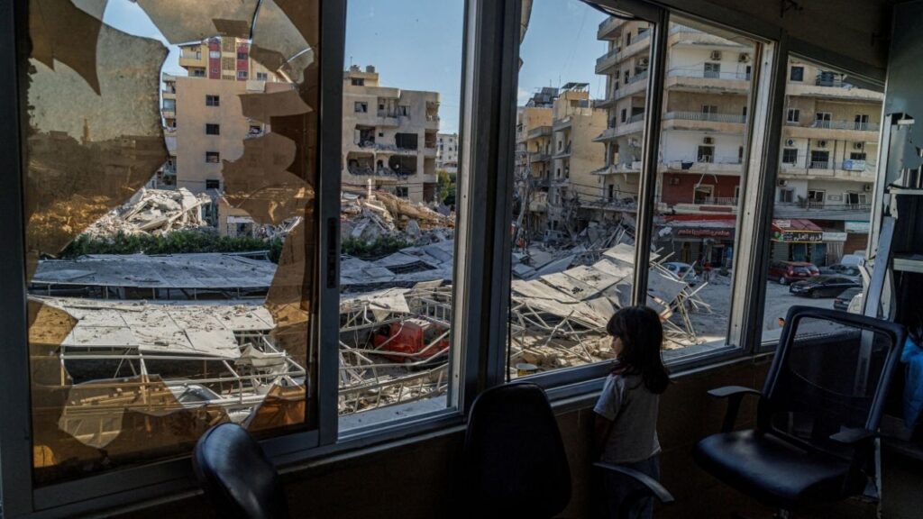 A displaced girl stands at the broken window of Jabal Amel hospital where she has taken shelter with her family, overlooking buildings damaged by Israeli strikes, following a deal between the U.S. and Iran, in Tyre, southern Lebanon, June 16, 2026. (Reuters/Zohra Bensemra)