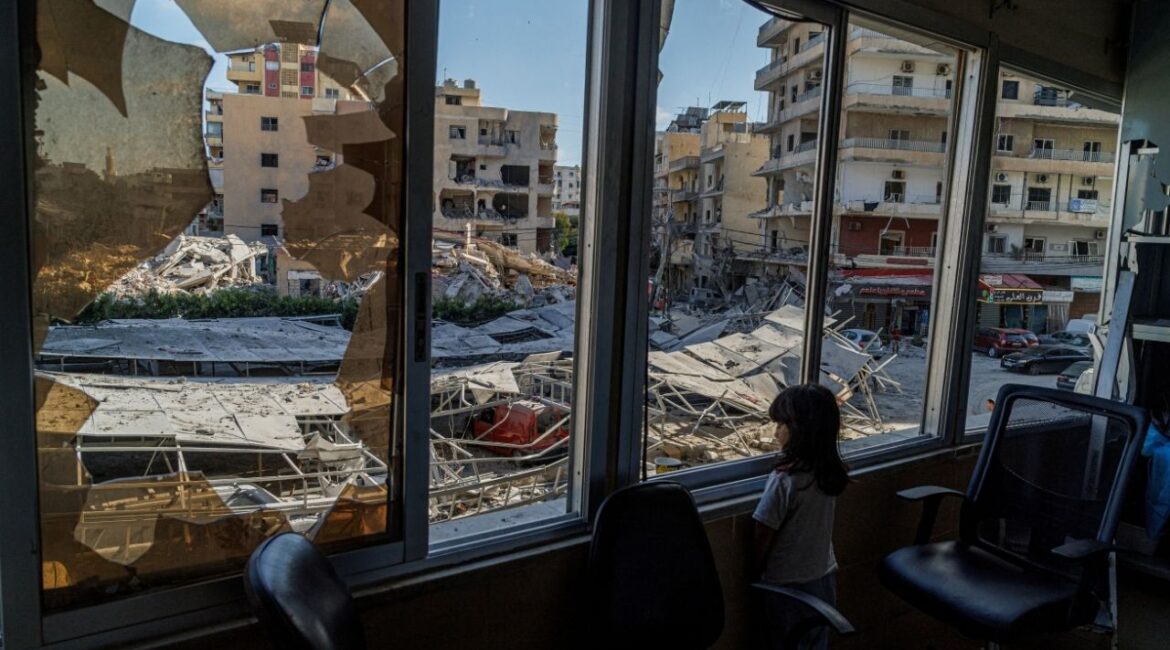 A displaced girl stands at the broken window of Jabal Amel hospital where she has taken shelter with her family, overlooking buildings damaged by Israeli strikes, following a deal between the U.S. and Iran, in Tyre, southern Lebanon, June 16, 2026. (Reuters/Zohra Bensemra)