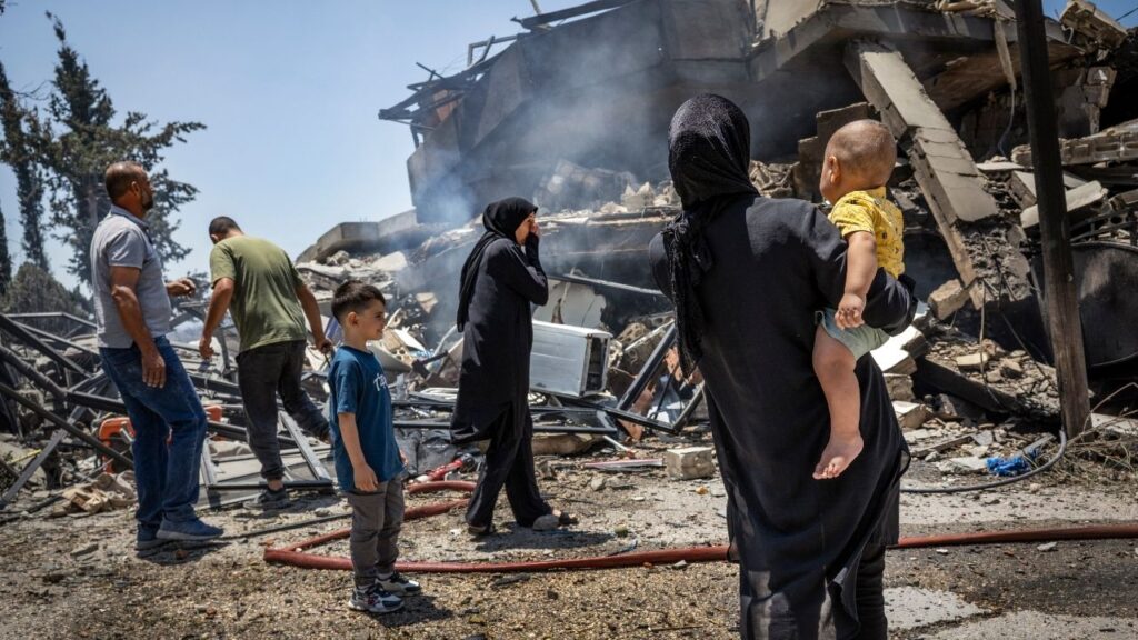A family gathers near their destroyed home in Kfar Roummane, Lebanon, on Sunday, June 21, 2026. Vice President JD Vance said on Sunday that “great progress” had been made at the outset of U.S.-Iran talks in Switzerland but warned that they were “not going to solve every disagreement,” as the conflict between Israel and Hezbollah in Lebanon and the status of the Strait of Hormuz loomed over efforts to reach a broader peace deal. (David Guttenfelder/The New York Times)
