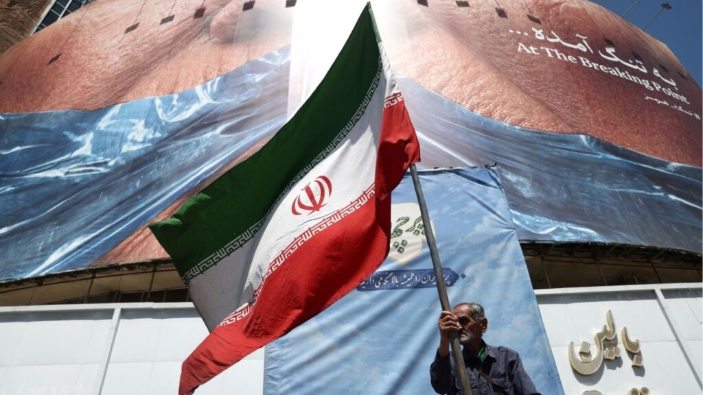 A man holds an Iranian flag near an anti-U.S. billboard depicting U.S. President Donald Trump and the Strait of Hormuz, in Tehran, Iran, May 30, 2026. Majid Asgaripour/WANA (West Asia News Agency) via Reuters
