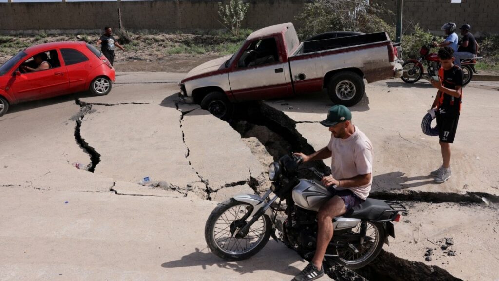 A man sits on a bike on a damaged road after earthquakes hit the country, in La Guaira, Venezuela, June 25, 2026. REUTERS/Gaby Oraa