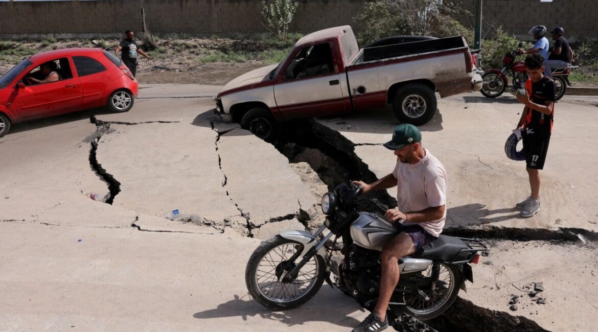 A man sits on a bike on a damaged road after earthquakes hit the country, in La Guaira, Venezuela, June 25, 2026. REUTERS/Gaby Oraa