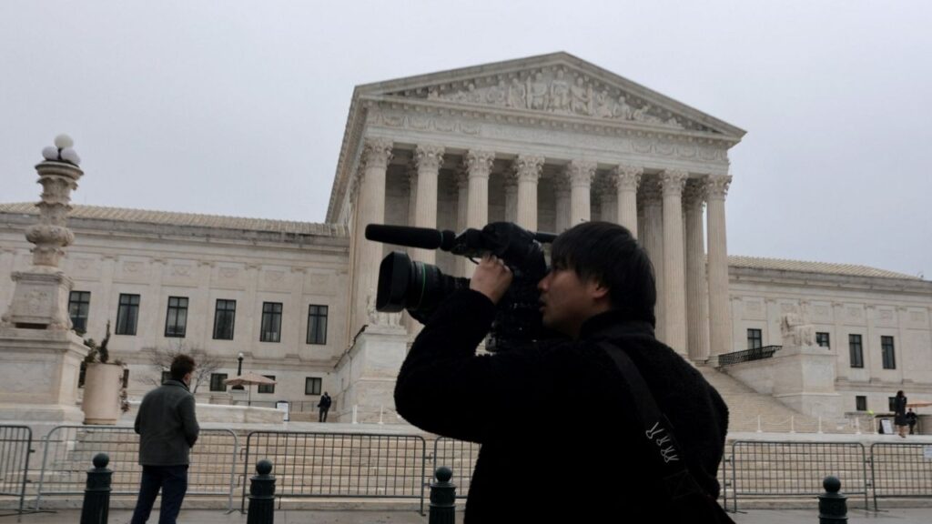 A person uses a video camera to record outside the U.S. Supreme Court building in Washington, D.C., U.S., February 20, 2026. (Reuters/Jonathan Ernst)