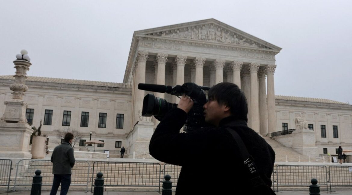 A person uses a video camera to record outside the U.S. Supreme Court building in Washington, D.C., U.S., February 20, 2026. (Reuters/Jonathan Ernst)