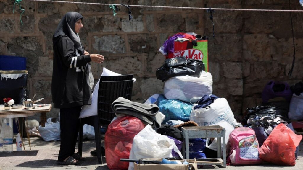 A woman stands near her belongings on a sidewalk in Beirut, where she and her family have been living in a tent, as she prepares to return home following an interim deal between the U.S. and Iran, in Beirut, Lebanon, June 24, 2026. (Reuters/Khalil Ashawi)