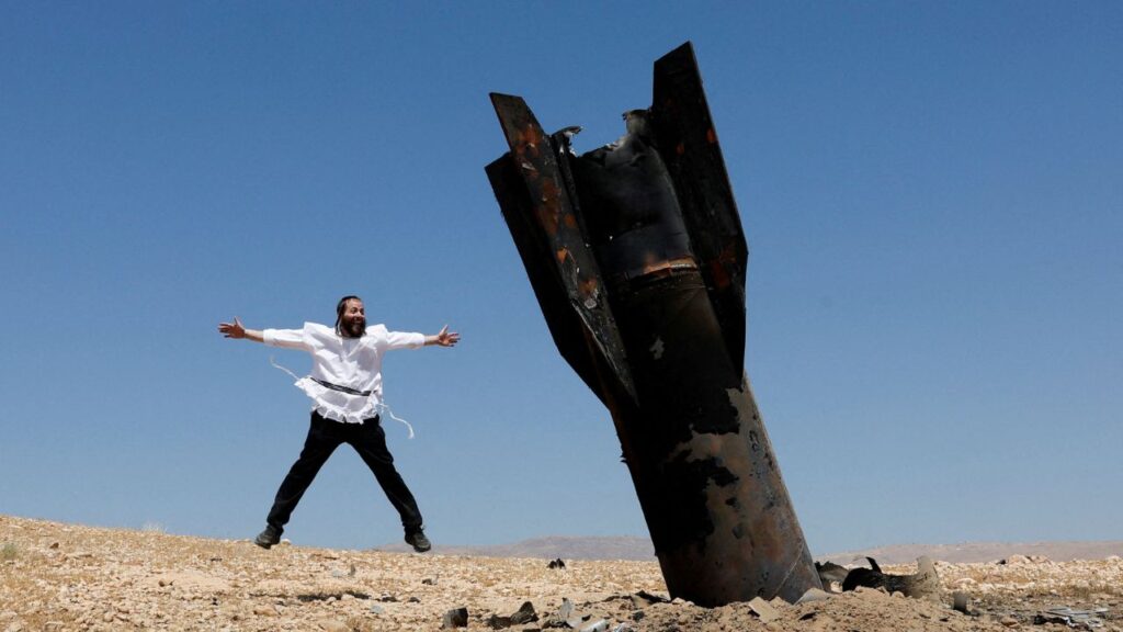 An Israeli ultra-Orthodox Jewish man reacts near a part of a missile protruding from the ground, following strikes from Iran, in the central Israeli-occupied West Bank, June 8, 2026. (Reuters/Ammar Awad)
