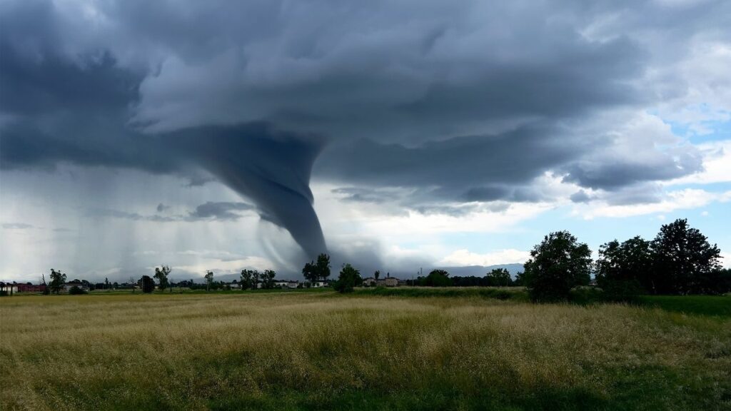 Asset id: 2472165531 Tornado forming over farmland, dramatic storm clouds touching ground