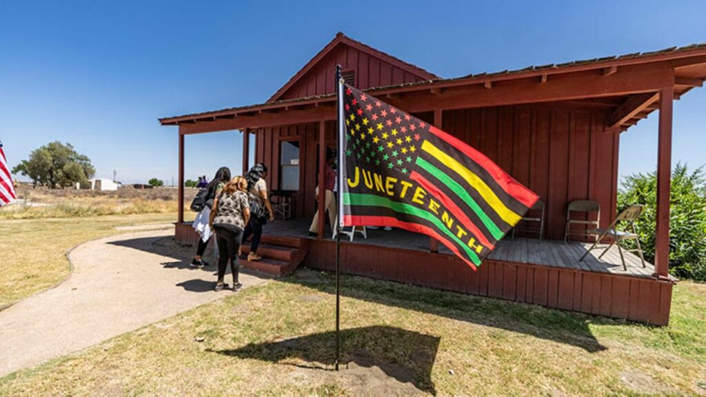 Image of a Juneteenth flag and visitors at Colonel Allensworth State Historic Park in Tulare County