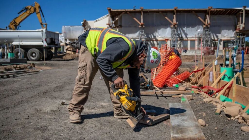 Image of a construction worker bending over to work at a project site