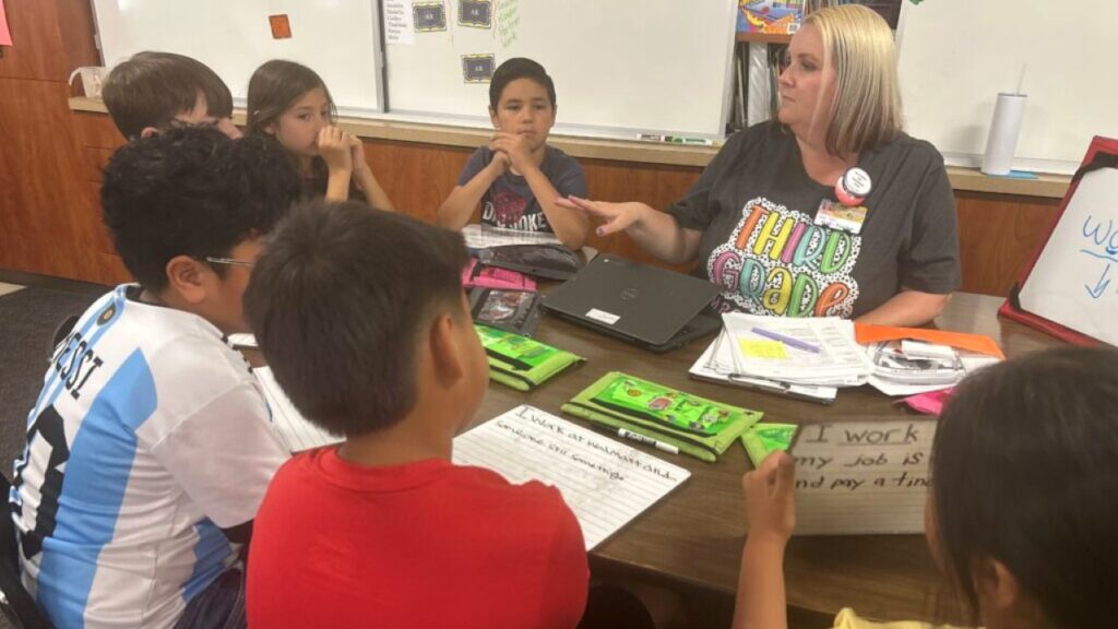 Image of a teacher working with her students who are seated around a table