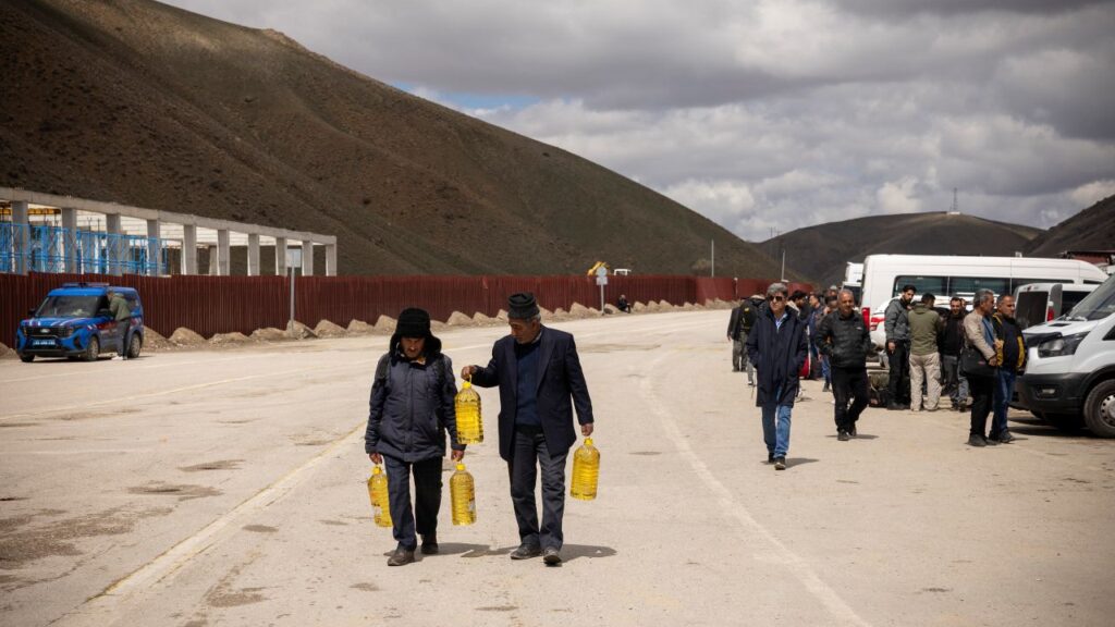 Image of two Iranians carrying cooking oil in bottles across the Turkish border