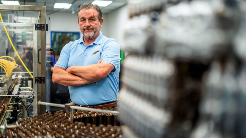Image of Vince Sanders in a powder blue shirt standing with his arms crossed in his kratom processing facility