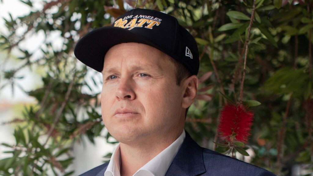 Image of Los Angeles mayoral candidate Spencer Pratt facing left. He's wearing a blue blazer, white open collar shirt and a baseball cap