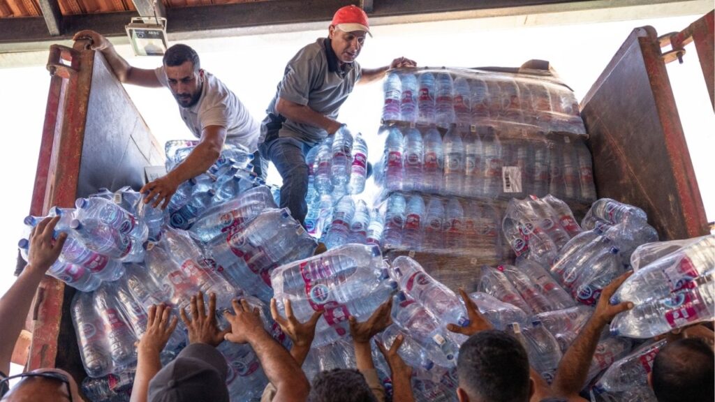 Residents unload bottles of water as they receive aid from a convoy run by L'Œuvre d'Orient, Caritas and UNIFIL that arrived from Beirut at a Christian church in Deir Mimas, southern Lebanon, on Friday, June 26, 2026. (David Guttenfelder/The New York Times)