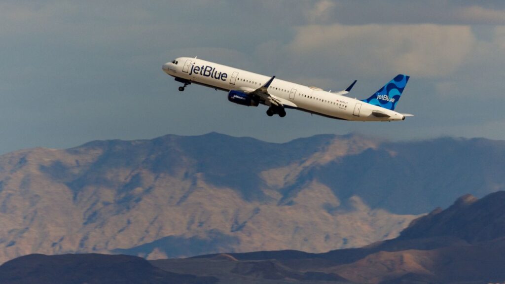 Image of a JetBlue commercial jet facing left and rising in the sky