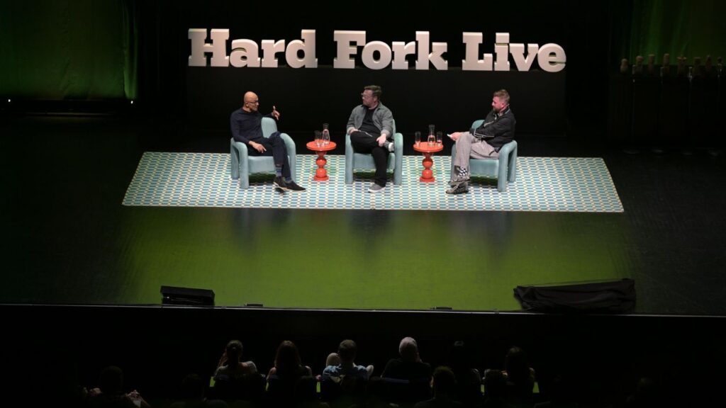 Satya Nadella, left, the chief executive of Microsoft, at the Hard Fork Live event in San Francisco, June 10, 2026. Nadella addressed the backlash against artificial intelligence and President Donald Trump’s comments about Americans sharing in the wealth of A.I. (Mike Kai Chen/The New York Times)
