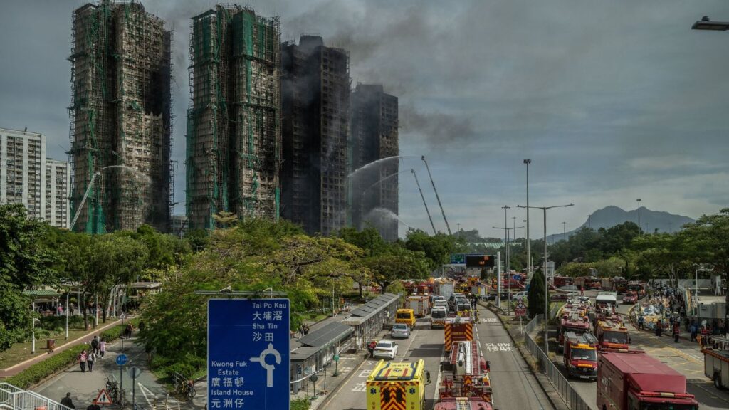 Smoke rises from the Wang Fuk Court apartment complex in Hong Kong on Nov. 27, 2025.The Hong Kong government said on Wednesday that it had charged seven people and two companies with dozens of offenses, including manslaughter, in relation to the city’s worst fire in generations. (Lam Yik Fei/The New York Times)