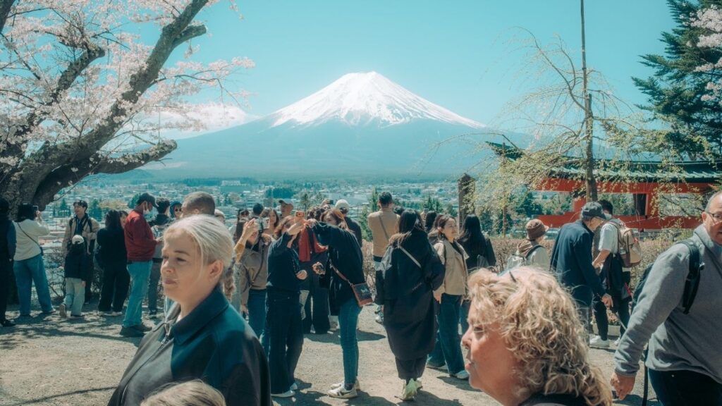 Tourists gather to view Mount Fuji in Fujiyoshida, Japan, April 8, 2026. Japan said that it will raise the price of some tourist visas by more than 400 percent starting in July 2026, the latest move in Prime Minister Sanae Takaichi’s campaign to tightly regulate entries by foreign nationals. Tourists from the United States and some 70 other countries will be exempted. (Kentaro Takahashi/The New York Times)