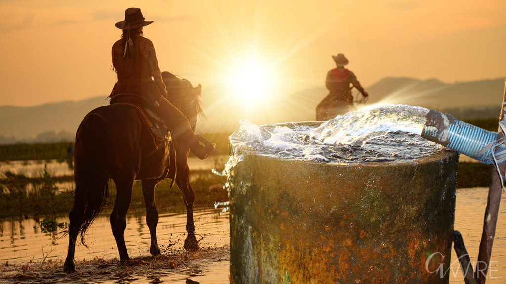 Composite image of two cowboys on horses riding past a standpipe spewing groundwater with a rising sun in the background