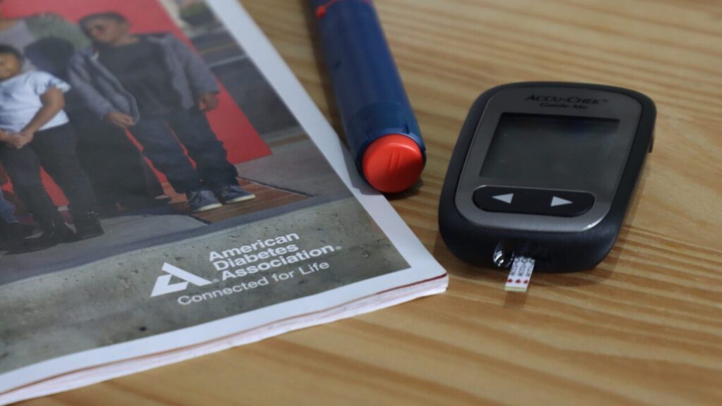Image of a blood sugar monitor, insulin injector, and an American Diabetes Association pamphlet