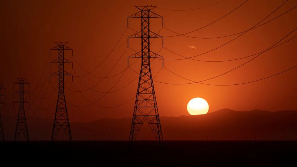 Image of a setting sun bathing rural Fresno County electrical transmission lines in red hues on a scorching hot day
