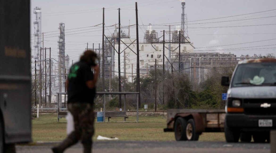 A man passes by at an Exxon gas station as a flare stack burns in the distance at the Formosa Point Comfort Plant in Point Comfort, Texas, U.S., January 8, 2026. (Reuters File)
