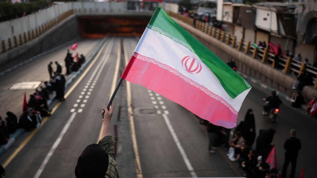 A mourner waves an Iranian flag on the day of the funeral procession for Iran's late Supreme Leader Ayatollah Ali Khamenei, who was killed on February 28 in Israeli and U.S. airstrikes, in Tehran, Iran, July 6, 2026. (Reuters/Alkis Konstantinidis)