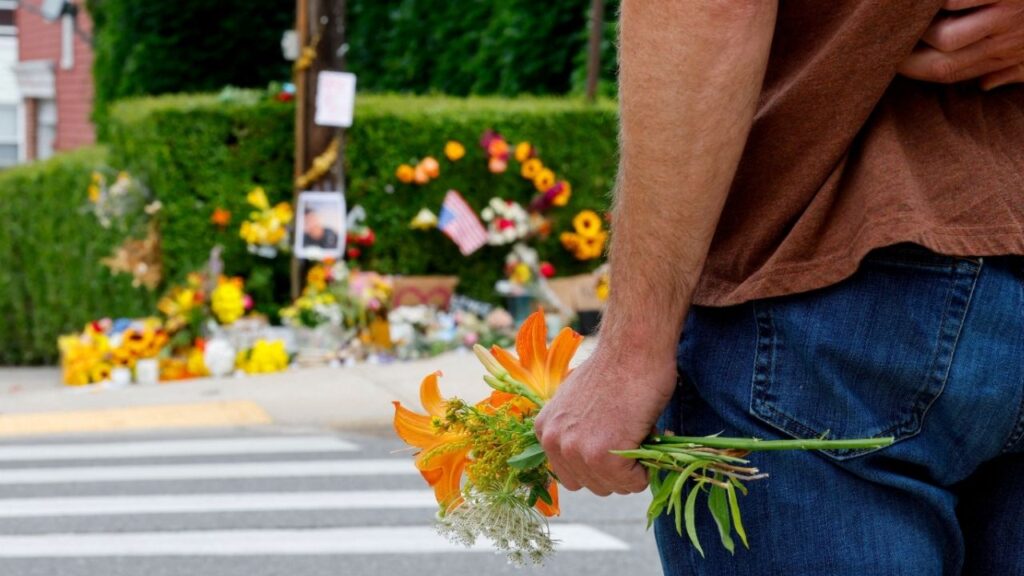 A person holds flowers while standing across the street from a makeshift street side memorial, a day after a U.S. Immigration and Customs Enforcement (ICE) agents fatally shot a driver, in Biddeford, Maine, U.S., July 14, 2026. (Reuters/CJ Gunther)