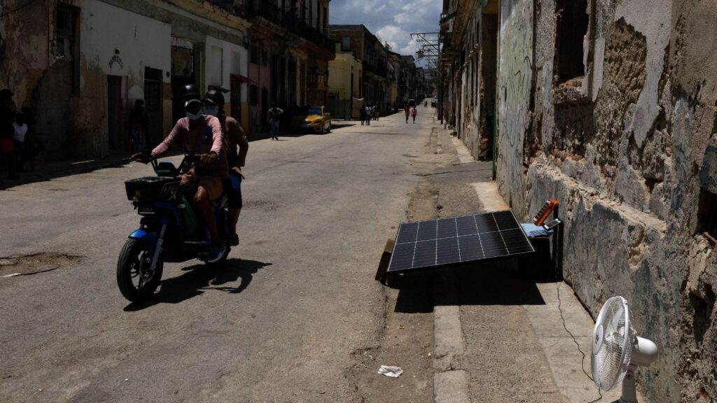 A person rides an electric motorcycle past a solar panel on a street as Cuba's national electric grid collapsed at midday, leaving around 10 million people without power, in Havana, Cuba July 6, 2026. (Reuters/Norlys Perez)