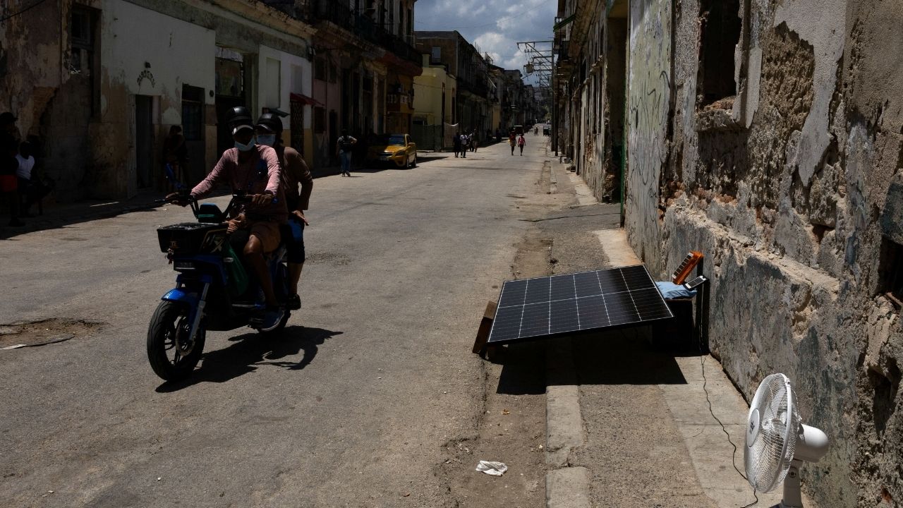 A person rides an electric motorcycle past a solar panel on a street as Cuba's national electric grid collapsed at midday, leaving around 10 million people without power, in Havana, Cuba July 6, 2026. (Reuters/Norlys Perez)