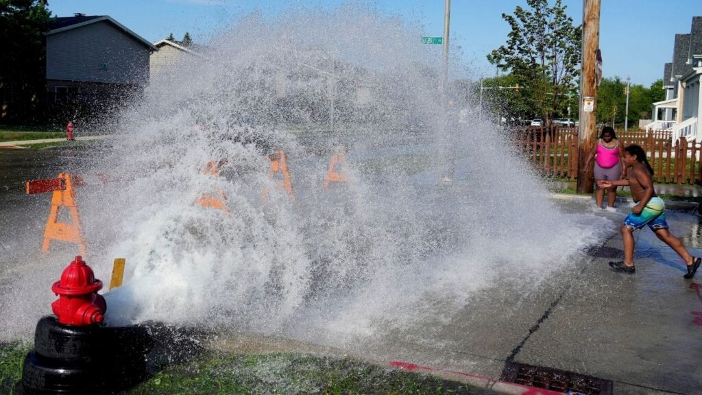 An unauthorized fire hydrant opening offers temporary relief from extreme heat for children in Milwaukee, Wisconsin, U.S. June 29, 2026. Angela Peterson/USA Today Network via REUTERS.
