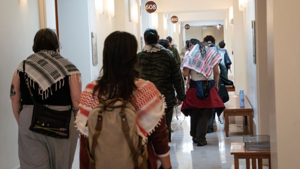 Image of the backs on people walking through a court hallway