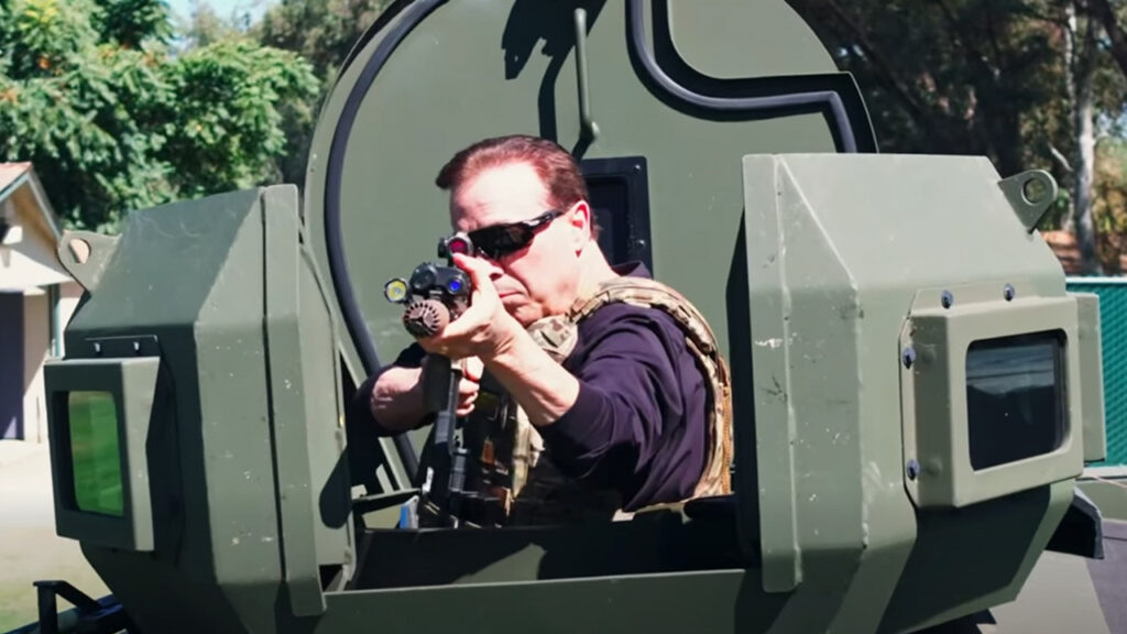 Image of Fresno County Supervior Garry Bredefeld pointing a high-powered gun from a SWAT vehicle,
