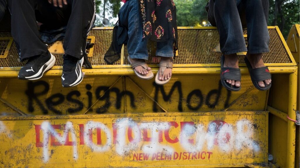 Supporters of the Cockroach Janta Party sit on barricades, with graffiti that includes the words “Modi Chor,” meaning “Modi Thief,” after the resignation of India’s education minister in New Delhi on Saturday, July 25, 2026. The Cockroach Janta Party called an end to weeks of protests after the education minister resigned, a win for that movement even as deep-seated anger among young people remains. (Saumya Khandelwal/The New York Times)