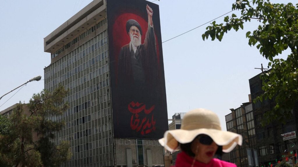 A woman walks by a billboard depicting Iran's late Supreme Leader Ayatollah Ali Khamenei, on a street in Tehran, Iran, July 21, 2026. (Majid Asgaripour/WANA (West Asia News Agency) via REUTERS)