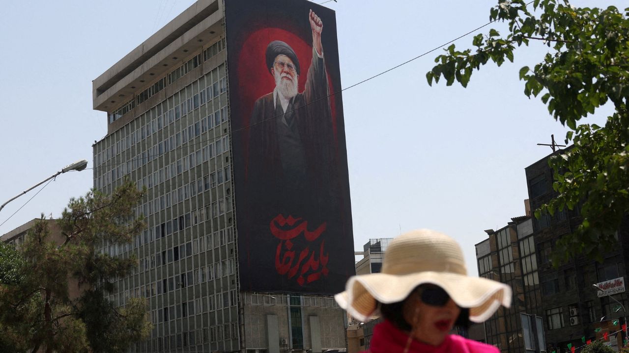 A woman walks by a billboard depicting Iran's late Supreme Leader Ayatollah Ali Khamenei, on a street in Tehran, Iran, July 21, 2026. (Majid Asgaripour/WANA (West Asia News Agency) via REUTERS)