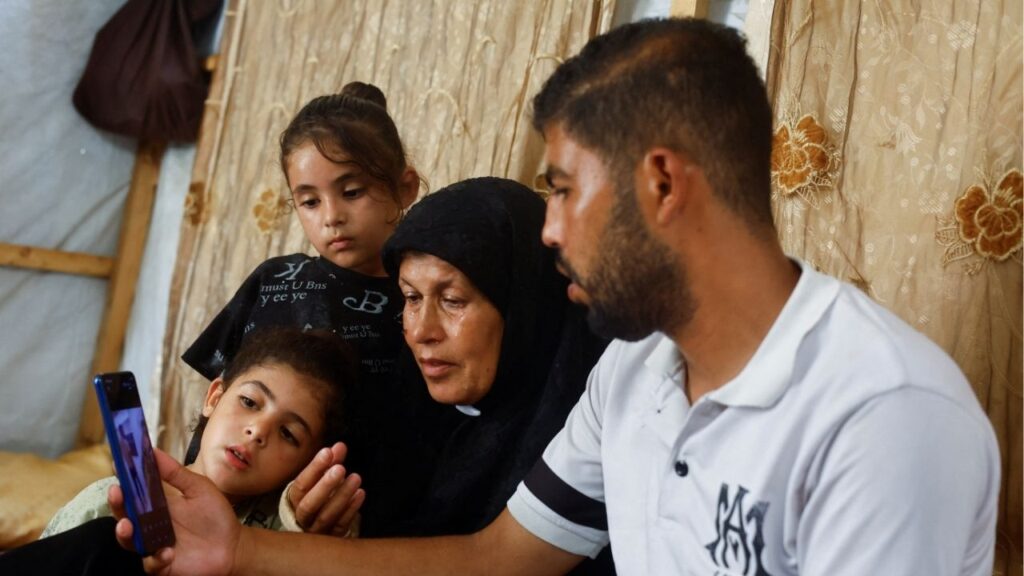 Joudeh Al-Ghoul, mother of Palestinian prisoner Ameen Al-Ghoul who is held by Israel, and family members look at a mobile phone displaying a widely circulated image believed to show him in custody, in Gaza City, July 4, 2026. Reuters/Mahmoud Issa