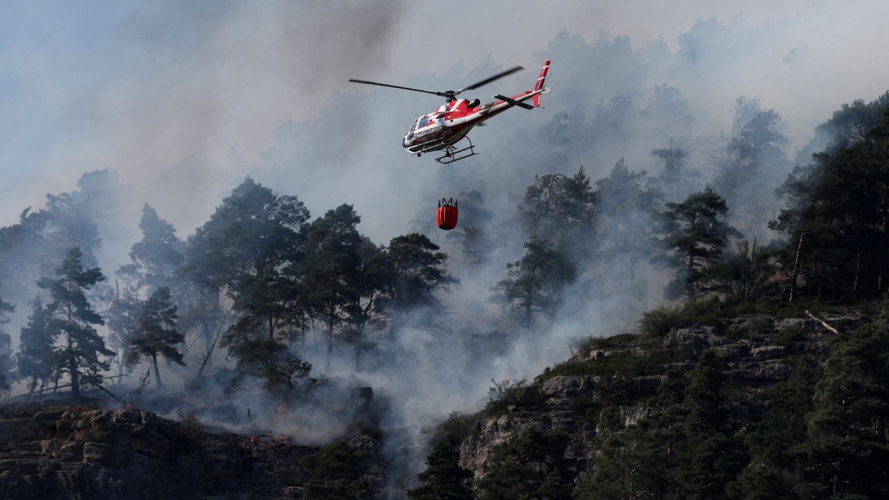 A firefighting helicopter flies over a wildfire in a mountain area near Freissinieres and L'Argentiere-la-Bessee in the Hautes-Alpes as drought conditions worsen following a heatwave and water shortages across much of France, July 22, 2026. (REUTERS/Alexandre Dimou)