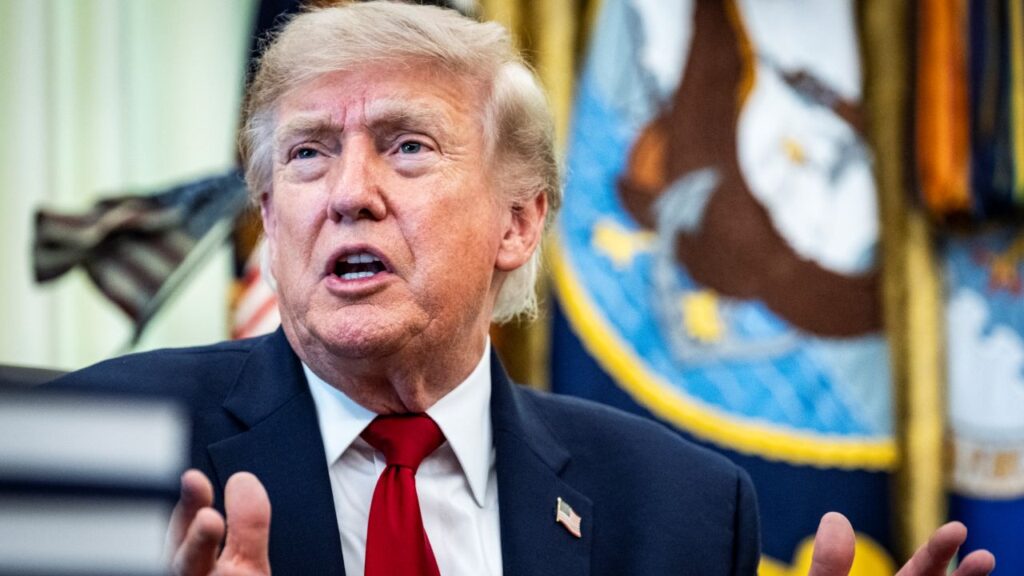 Image of President Trump in blue suit, white shirt, and red tie speaking while he faces left